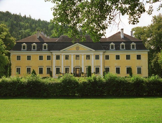 Schloss Gutenstein mit gelber Fassade und symmetrischer Architektur, umgeben von Bäumen und Rasen.