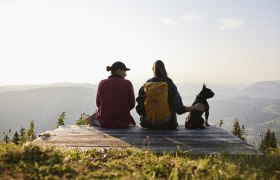 Zwei Frauen auf Aussichtbank mit Hund schauen vom Raxplateau in die Wiener Alpen