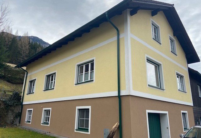 House view private room Jansch, © Wiener Alpen Two-storey yellow-brown house with white window frames and green downpipes.