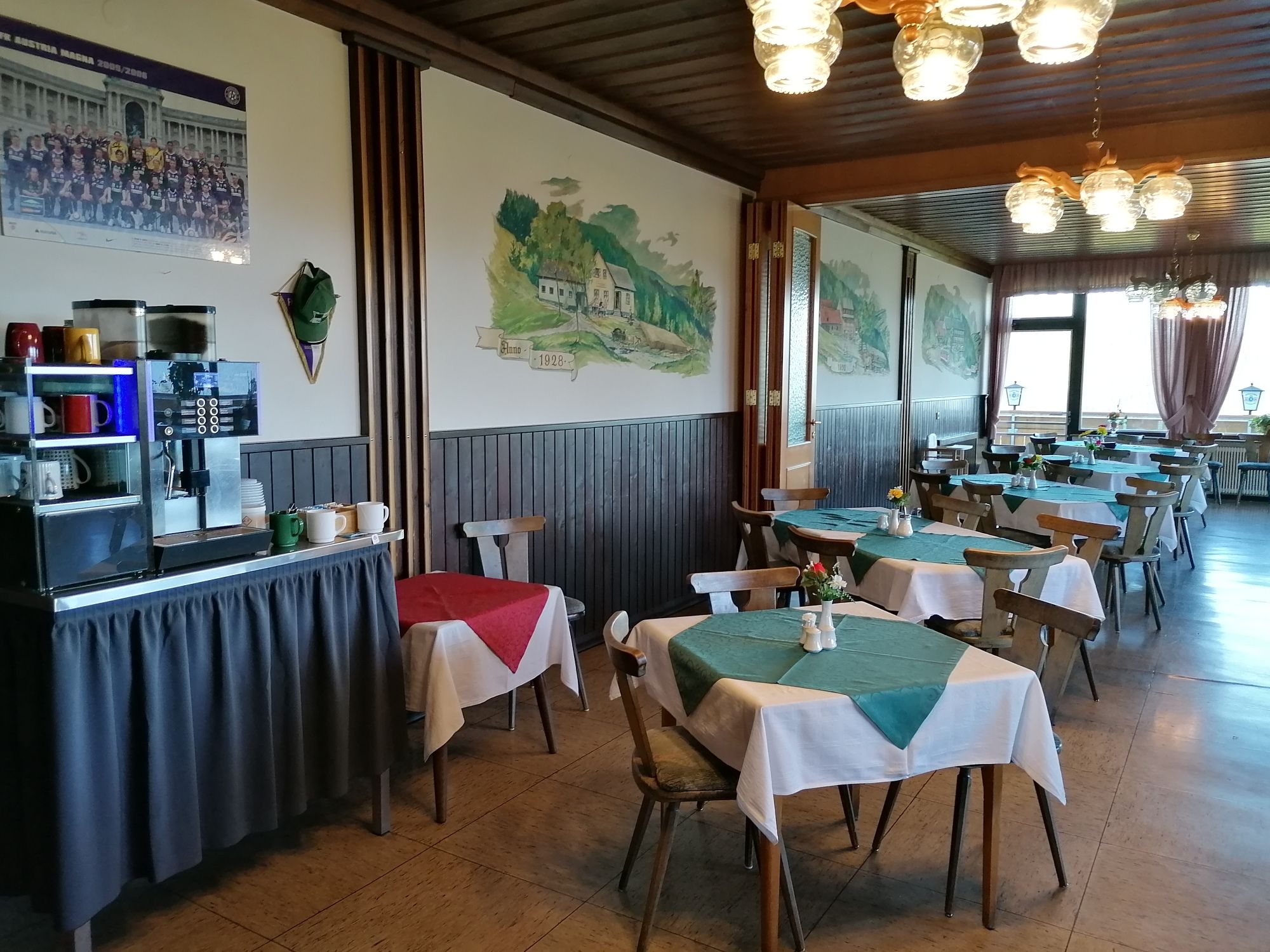 Innenansicht eines Restaurants mit Holzmöbeln und Tischdecken.