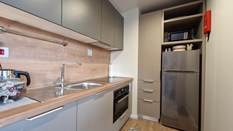 Modern kitchen with gray cabinets, stainless steel sink, stove and refrigerator.