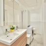 Modern bathroom with double washbasin, mirror, washing machine and WC.