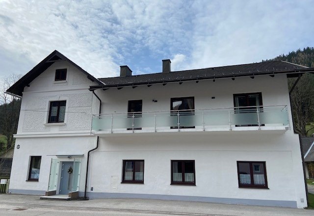 Privatzimmer Strasser, © Wiener Alpen Zweistöckiges weißes Haus mit Balkon und blauen Himmel im Hintergrund.