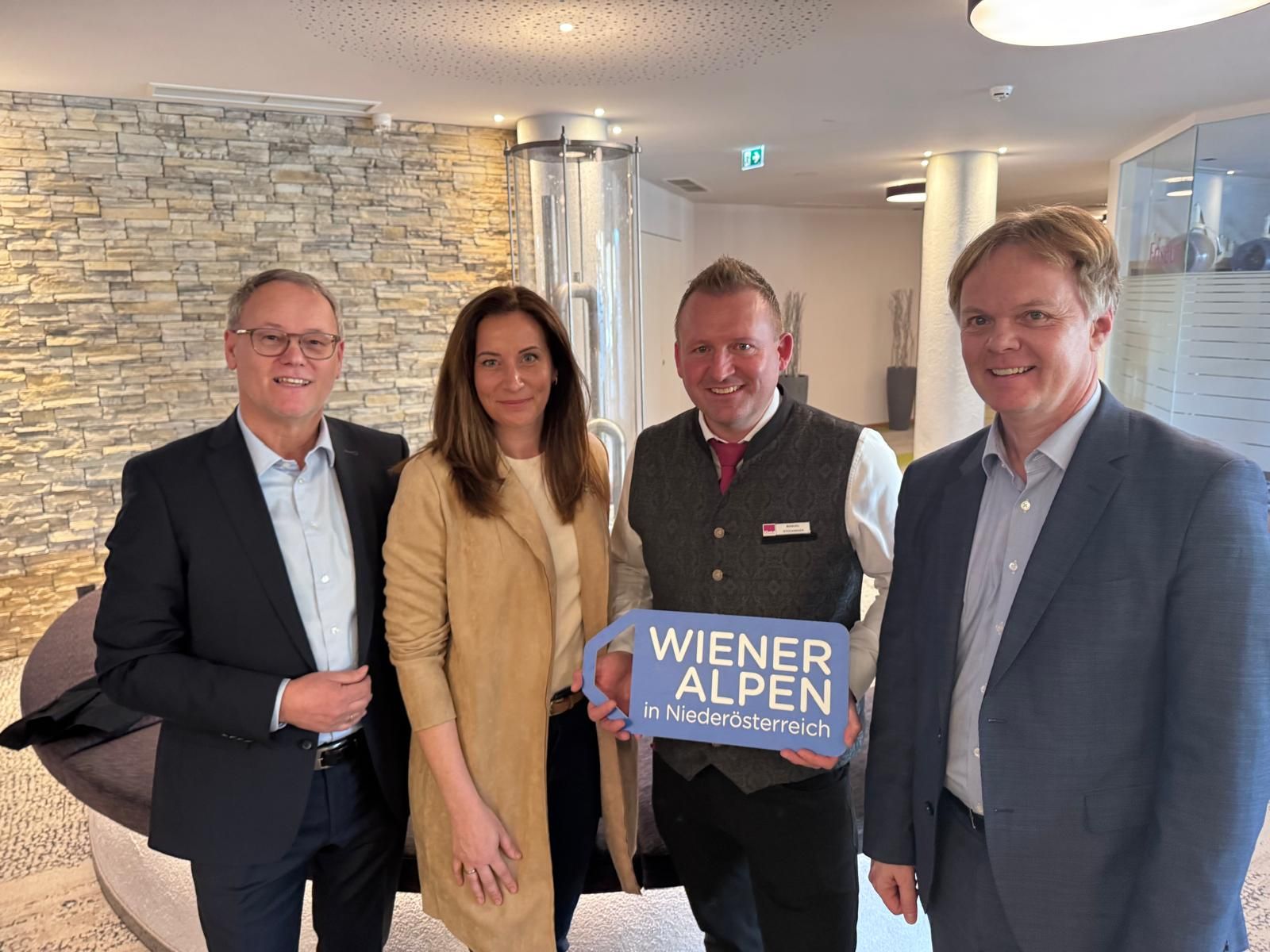 Vier Personen stehen nebeneinander und halten ein Logoschild in den Händen.