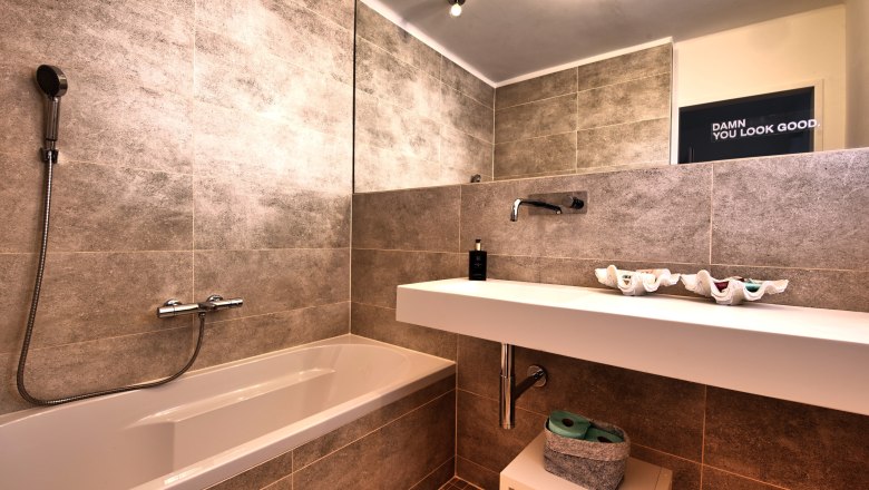 Modernes Badezimmer mit Badewanne, Waschbecken und großem Spiegel.