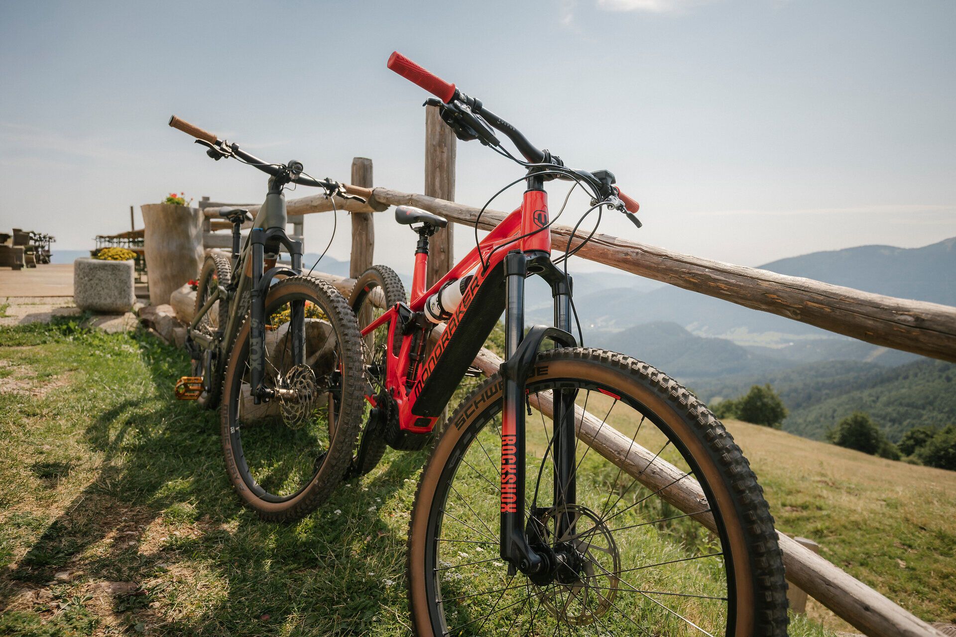 Mountain bikes leaning against a wooden fence with a panoramic view at the Almreserlhaus on the Schneeberg