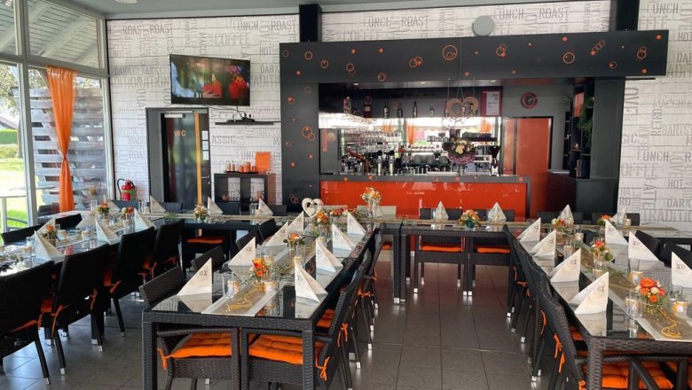 Ein stilvoll eingerichtetes Café mit gedeckten Tischen und einer Bar im Hintergrund.