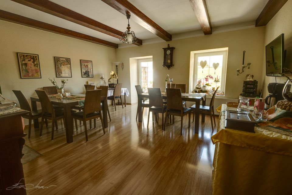 Gemütliches Frühstückszimmer mit Holzboden, Tischen und Stühlen, dekoriert mit Bildern und einer Wanduhr.