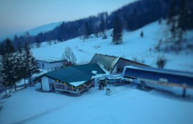 Winter landscape with buildings and ski lift in snowy surroundings.