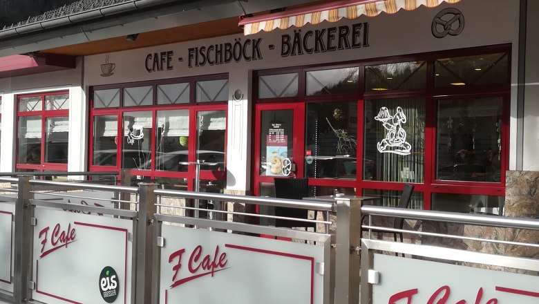 Au&szlig;enansicht eines Caf&eacute;s mit rotem Rahmen und Beschriftung 'Caf&eacute; Fischb&ouml;ck B&auml;ckerei'.