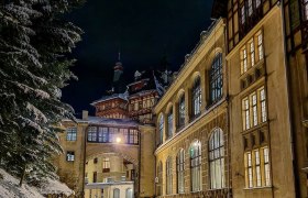 Historic building at night in winter, illuminated and covered in snow.