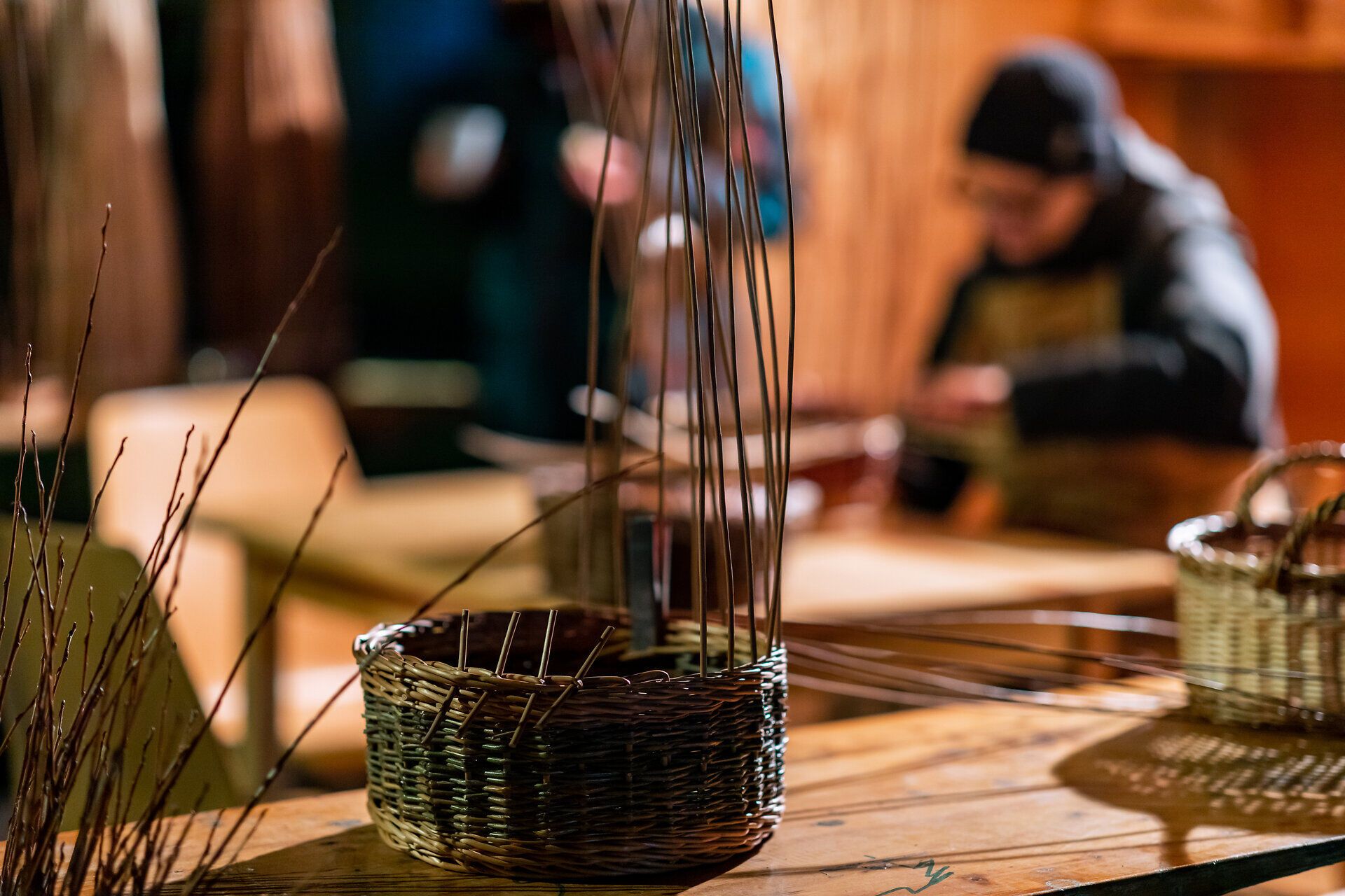 Detail eines Marktstands mit Körben und handwerklicher Arbeit im Hintergrund.