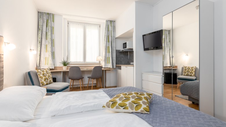Modernes Hotelzimmer mit Doppelbett, Schreibtisch, Stühlen und TV.
