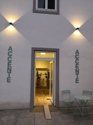 Eingang einer Boutique mit dem Namen 'Accente', beleuchtet bei Dämmerung.