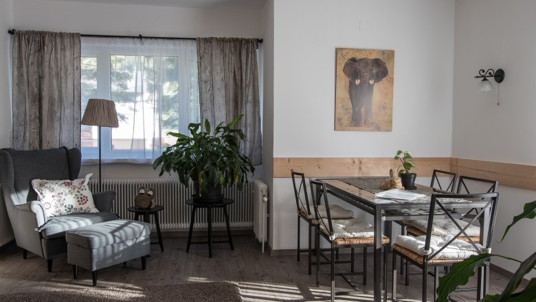 Gemütliches Wohnzimmer mit Sessel, Tisch und Pflanzen.