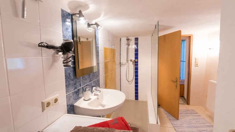 Ein Badezimmer mit Waschbecken, Spiegel, Dusche und Handtüchern.