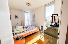 Helles Schlafzimmer mit Bett, Schreibtisch und Fenster.