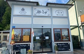 Außenansicht eines Cafés mit Schildern für Kaffee und Süßes.