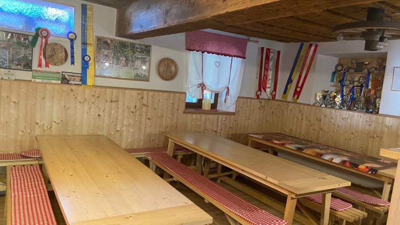 Cozy common room with wooden tables, benches and decorations on the walls.
