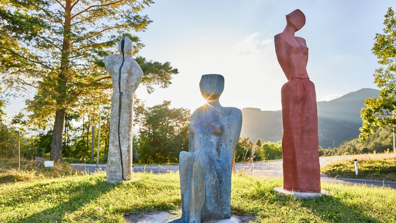 Three colorful sculptures on a meadow at sunset.