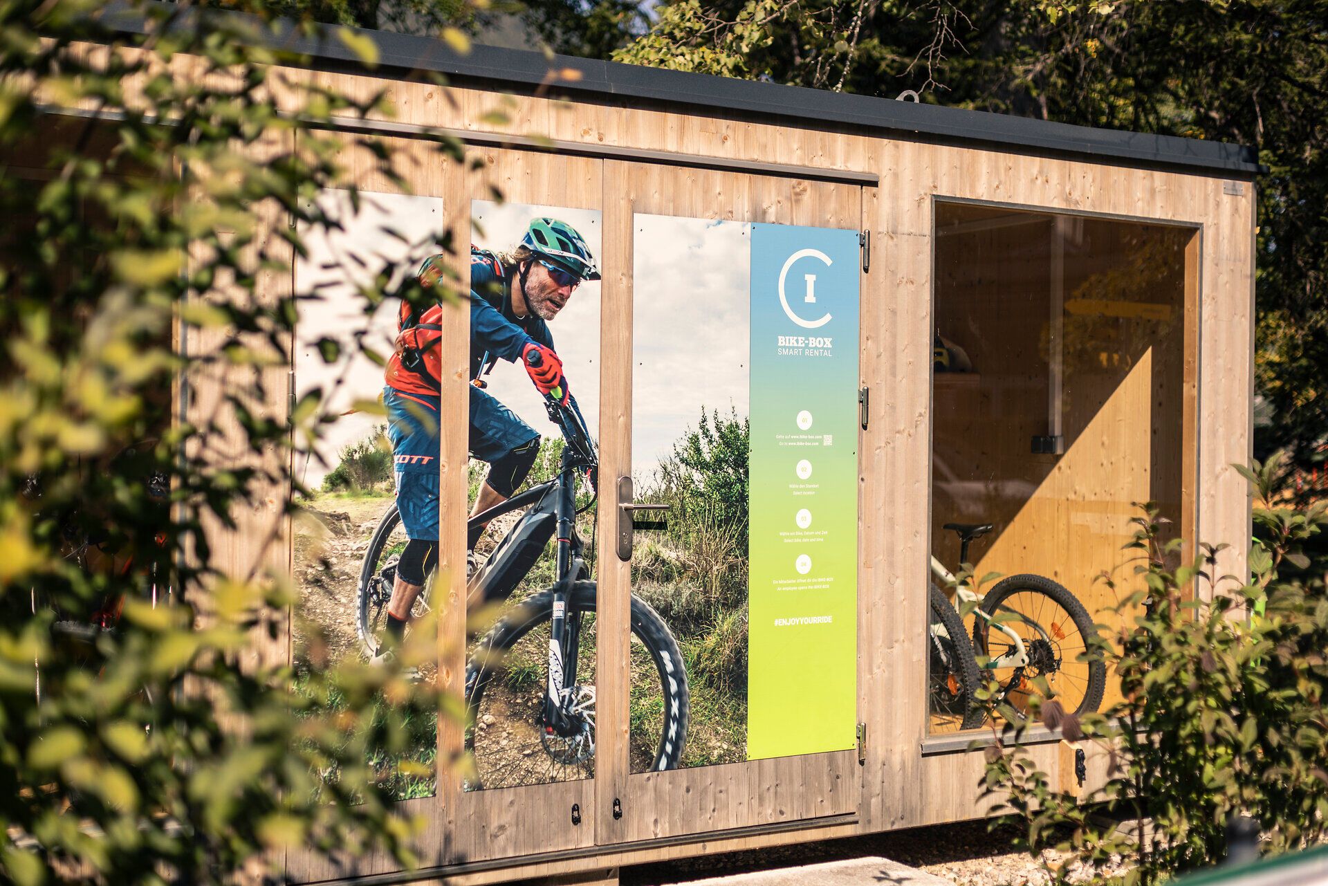 Beim Hotel Schneeberghof befindet sich eine Bike-Box, gebaut aus Holz mit großer Türe und Fenster und einem großflächigem Foto eines Mountainbikers 
