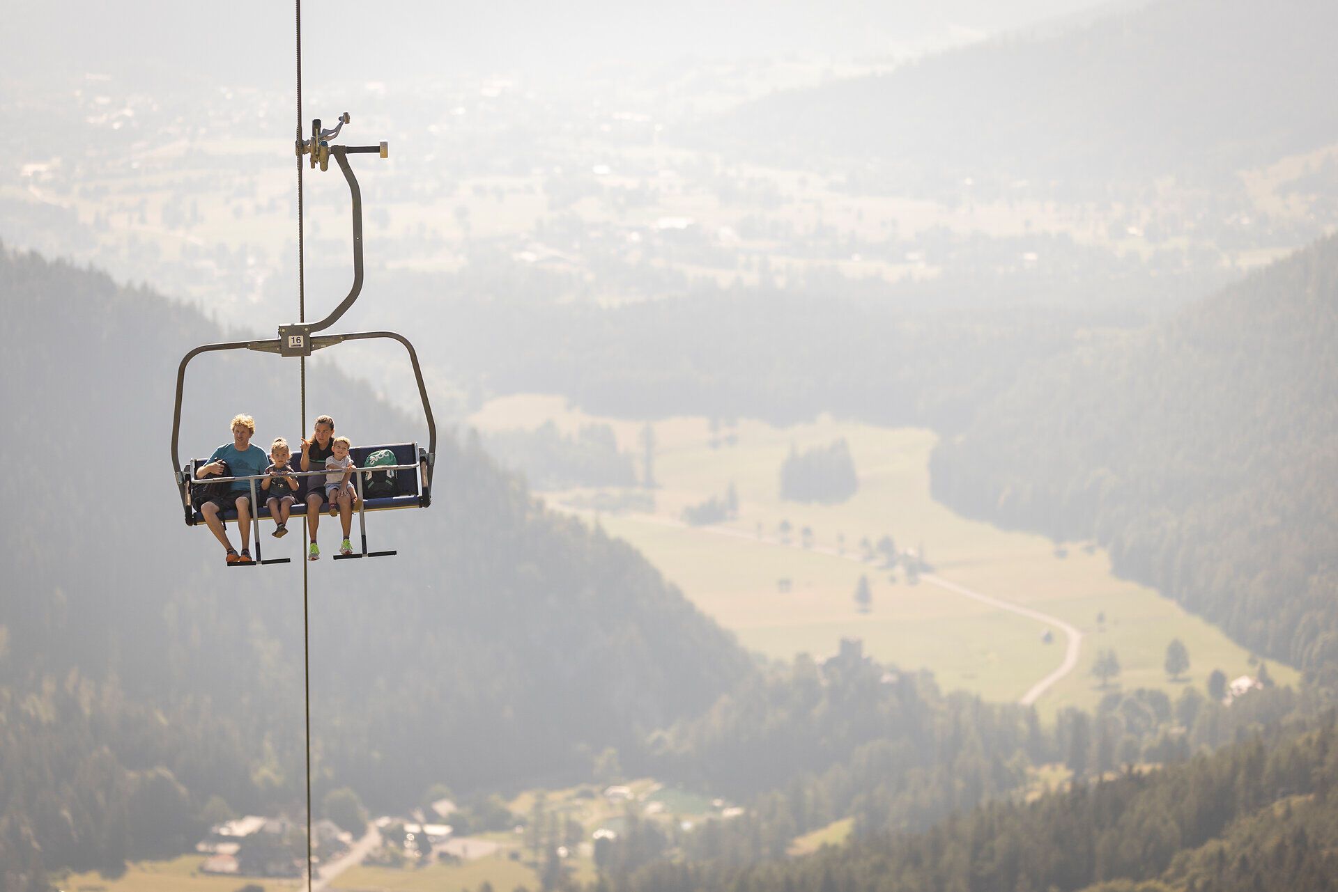 In der sanften Umarmung der Wiener Alpen schwebt eine Familie hoch über die malerische Landschaft. Die Kinder lachen und genießen die frische Bergluft, während sie auf dem Sessellift die atemberaubenden Ausblicke auf die umliegenden Täler und Wälder erleben. Ein unvergessliches Abenteuer in der Natur, das die Herzen aller Wanderer höher schlagen lässt.