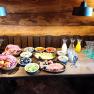 Breakfast buffet with bread rolls, cold cuts, cheese, vegetables, muesli and drinks on a wooden table.