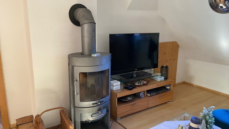 Living room with wood-burning stove, TV and decorated table.