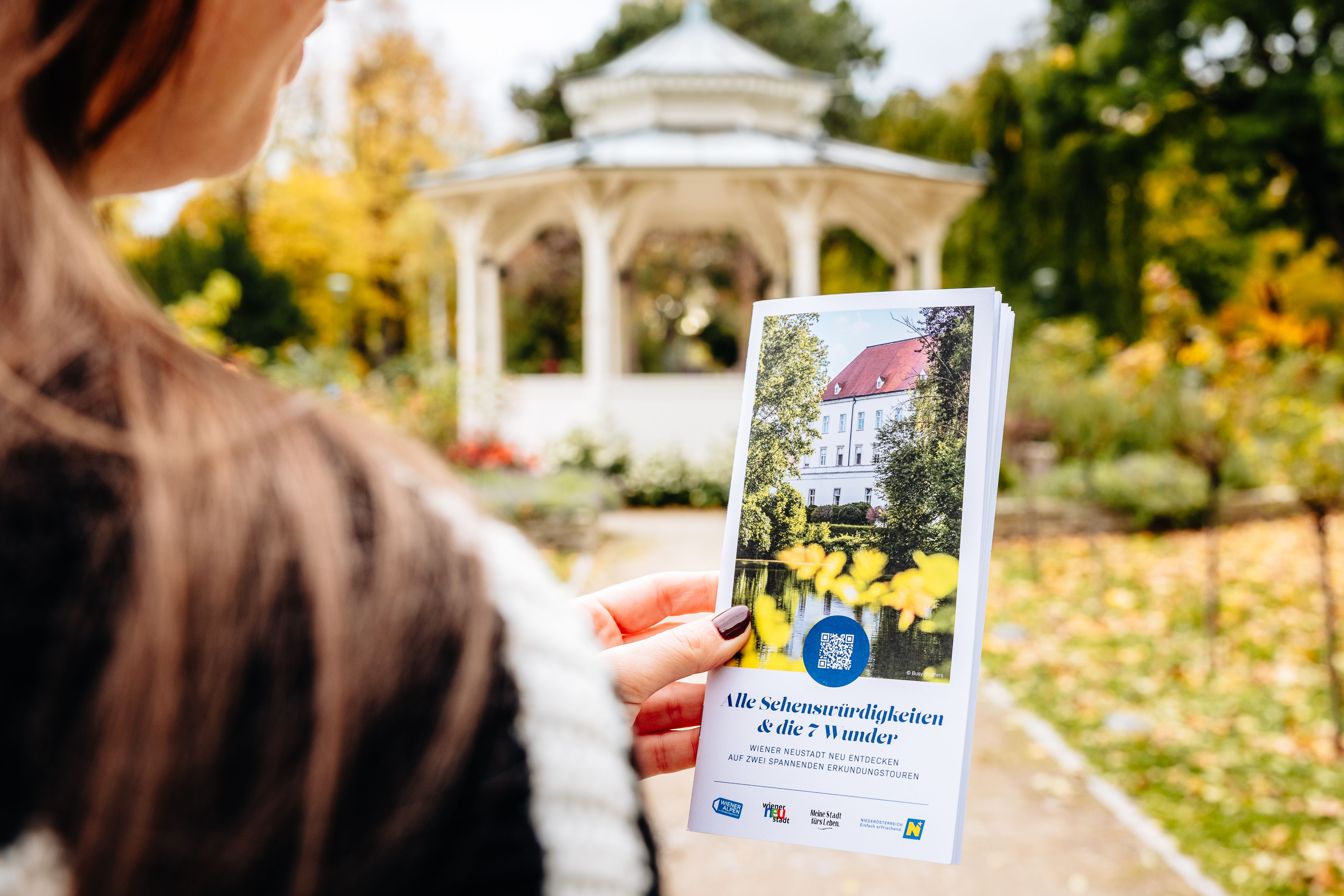 Frau mit Flyer vor einem Pavillon. 