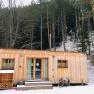 Small wooden house in a winter forest covered in snow.