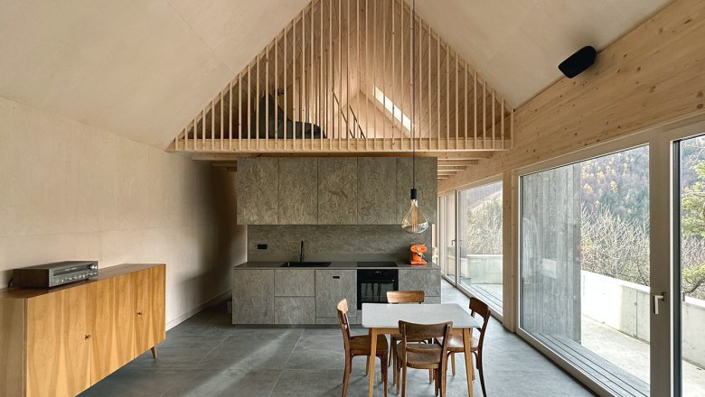 Moderne offene Küche mit Holzelementen und großen Fenstern.