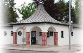 Kleines Gebäude mit rundem Dach und roten Backsteinpfeilern.