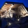 Ein beleuchtetes Holzchalet bei Nacht mit steinernen Treppenstufen im Vordergrund.