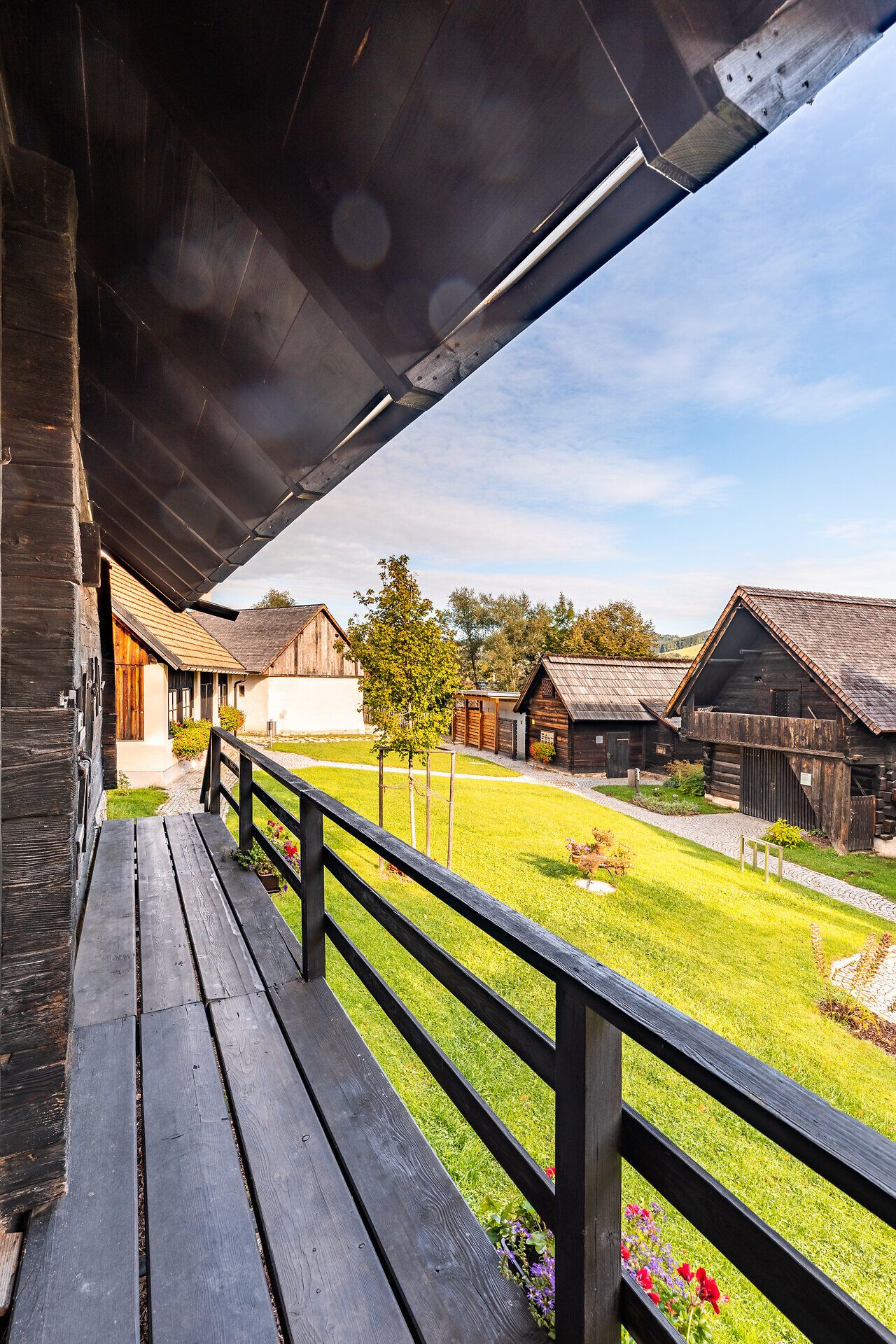Von der Terrasse eines Holzhauses blickt man auf die anderen Häuser im Museumsdorf Krumbach