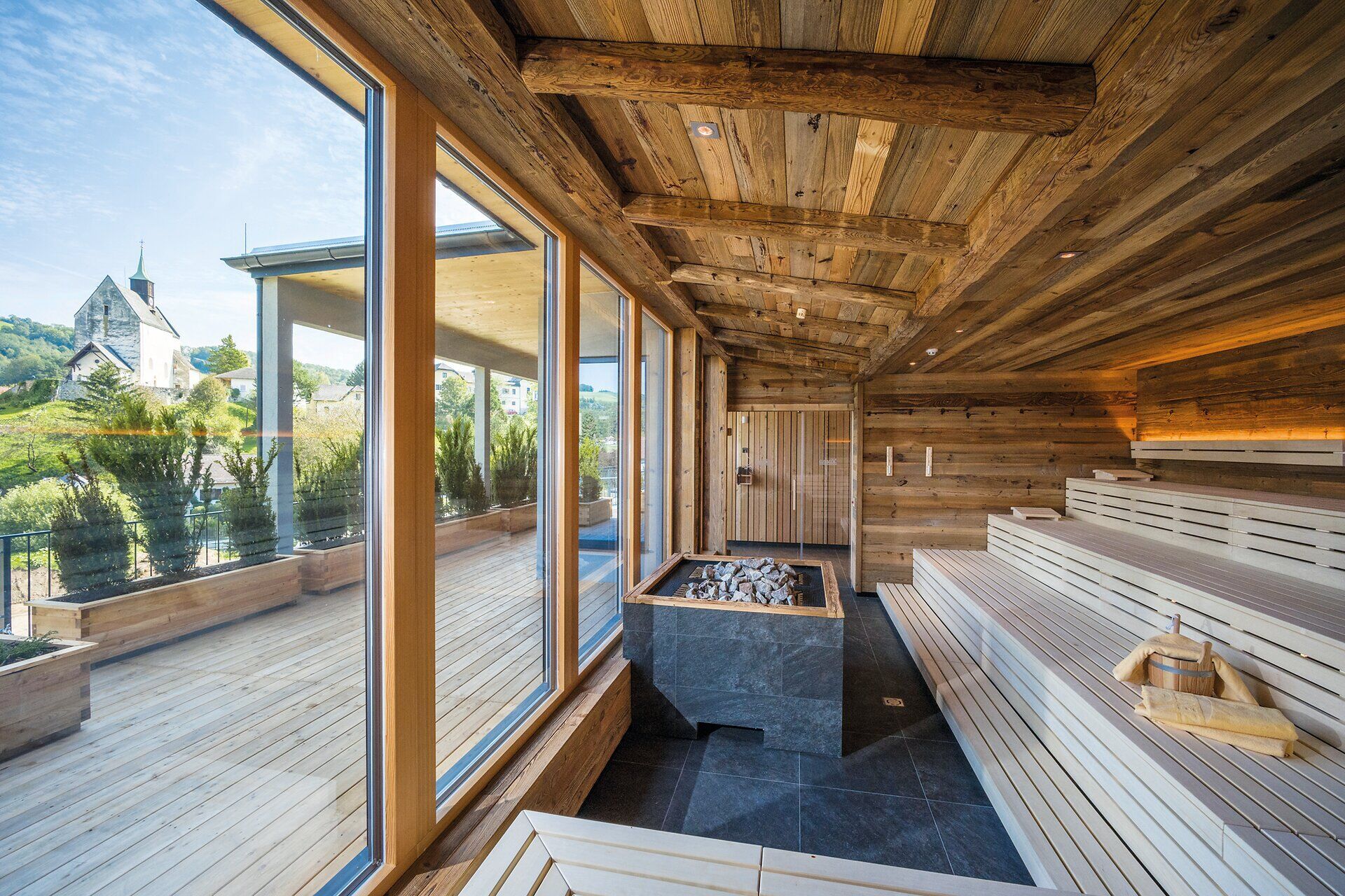 In der warmen, einladenden Atmosphäre des Wellnessbereichs entfaltet sich ein Gefühl der Ruhe und Entspannung. Die großen Fenster bieten einen atemberaubenden Blick auf die umliegende Natur, während das Holzinterieur eine harmonische Verbindung zur alpinen Umgebung schafft.