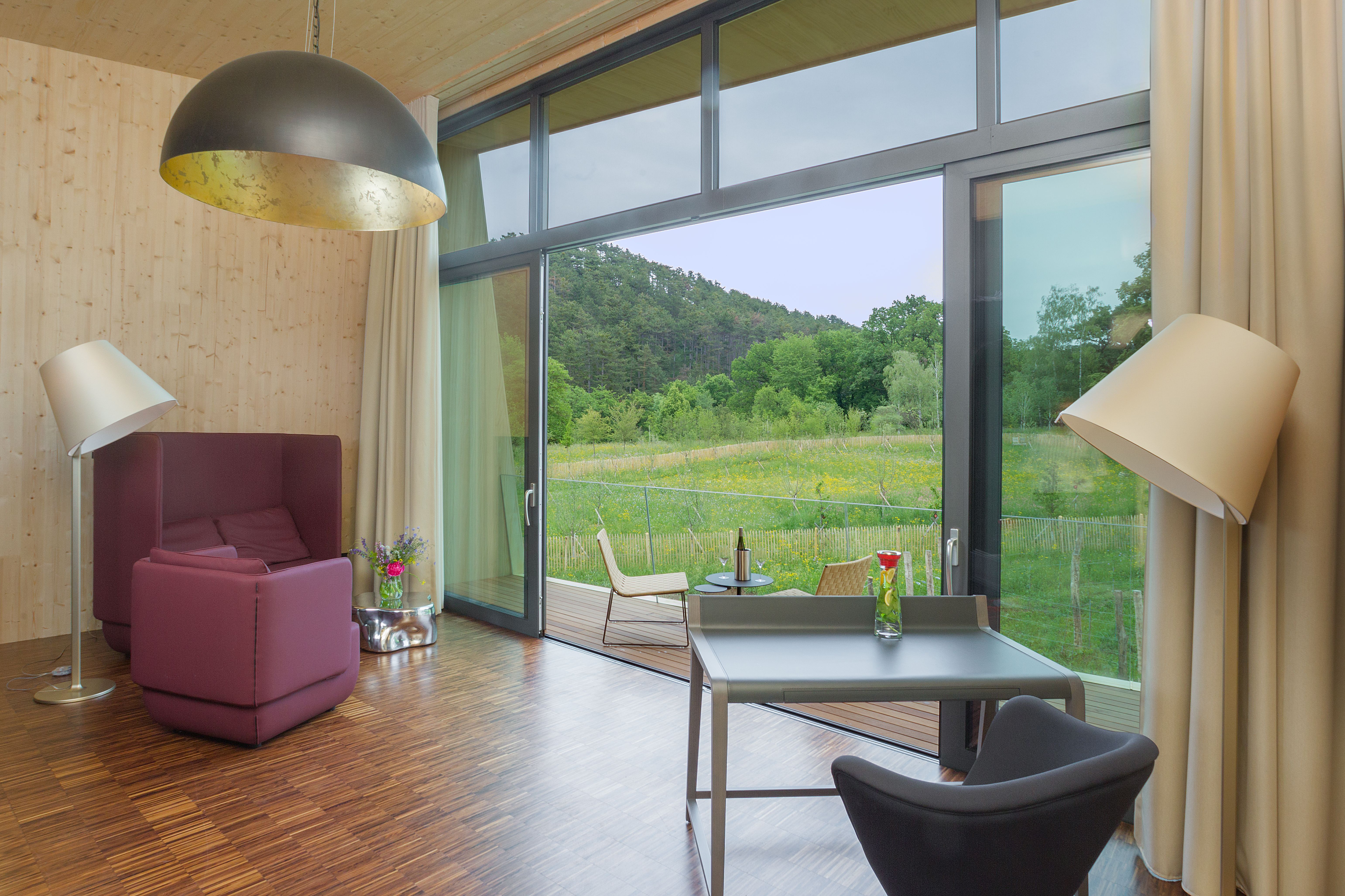 Ausblick aus der Terassentür eines modernen Hotelzimmers ins Grüne.