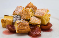 Gestückelter Sauerrahmschmarrn mit Zwetschkenröster auf einem weißen Teller.