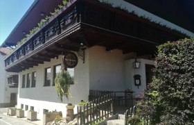 Traditionelles Gebäude mit Holzbalkon und Schild mit der Aufschrift "Mostschank".
