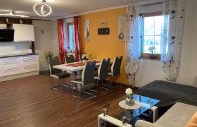 Moderne Wohnk&uuml;che mit Esstisch, St&uuml;hlen, Sofa und K&uuml;chenzeile.