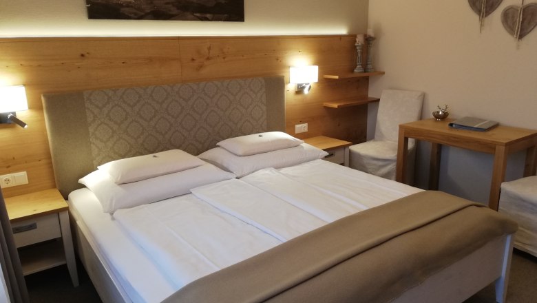 Gem&uuml;tliches Hotelzimmer mit Doppelbett, Holzm&ouml;beln und Wanddekoration.