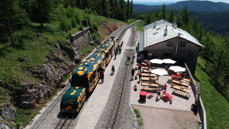 Bergbahnhof mit Zug und Café im Grünen.