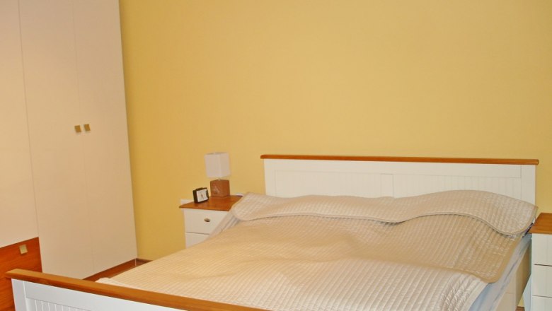 Bedroom with double bed, yellow wall and white closet.