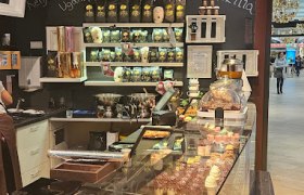 Innenansicht eines Cafés mit Theke, Gebäck und Kaffeebohnen im Regal.