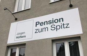 Fassade eines Gebäudes mit einem Schild der Pension zum Spitz.