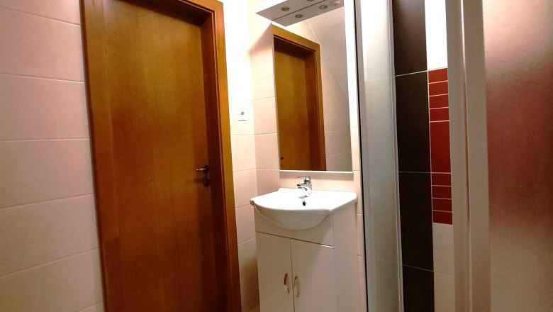 Modernes Badezimmer mit Holztür, Waschbecken und Dusche.