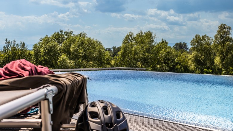 Liegestuhl mit Radkleidung und Helm am Infinity Pool des Grandhotel Niederösterreichischer Hof