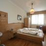 Comfortable hotel room with wooden furniture, double bed, washbasin and window with curtains.