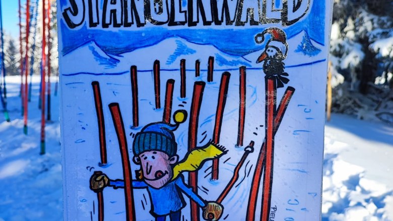 Schild im Schnee mit Comicfigur auf Skiern und Text 'Stangenwald, finde die schnellste Linie'.