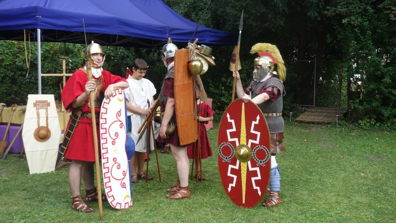 People in Roman armor during a historical re-enactment outdoors.
