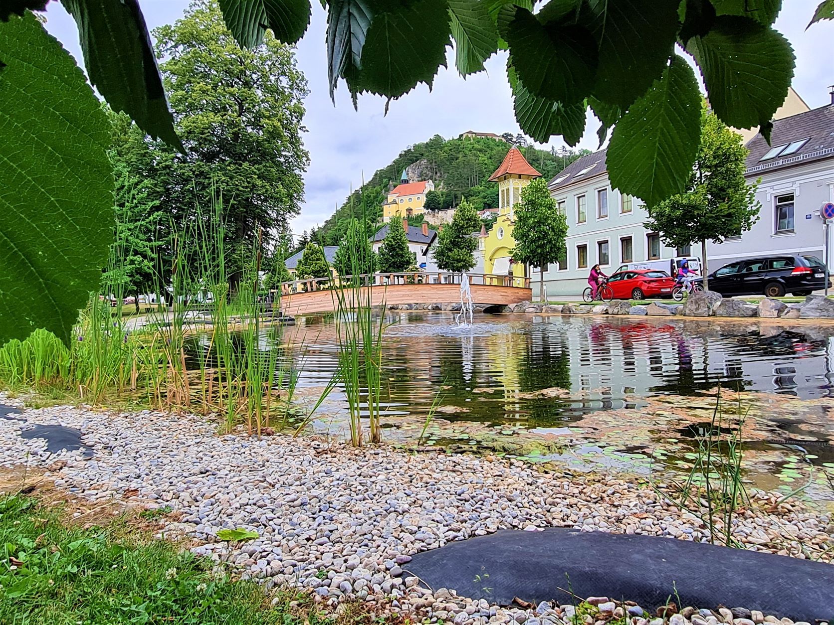 Ausblick von einen Park mit Teich und Brücke auf die Bergkirche Pitten
